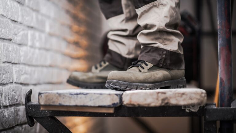 Radnik stoji na skeli u zaštitnim radnim patikama koje imaju ojačan đon i stabilno prijanjanje