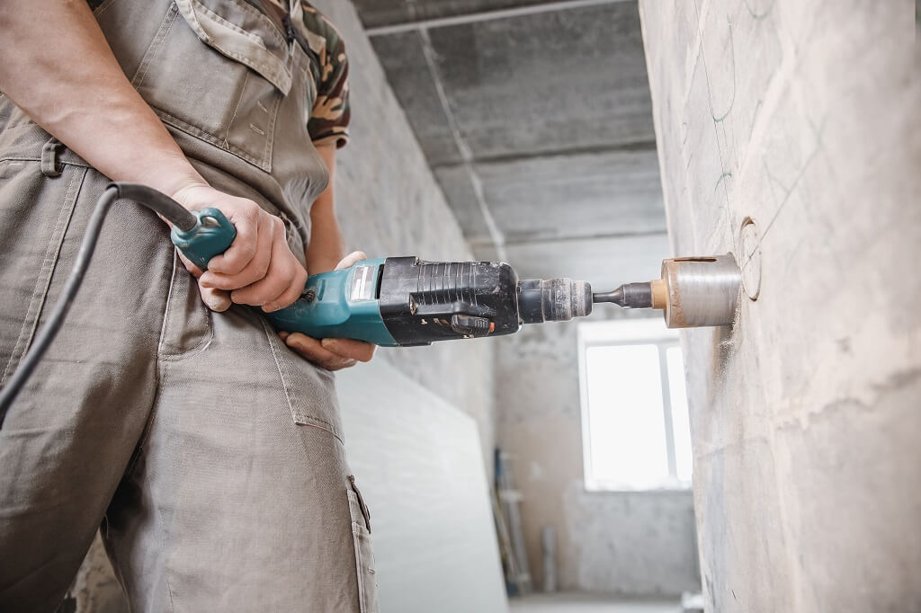 Radnik koristi električnu bušilicu sa krunom za precizno bušenje otvora u betonskom zidu