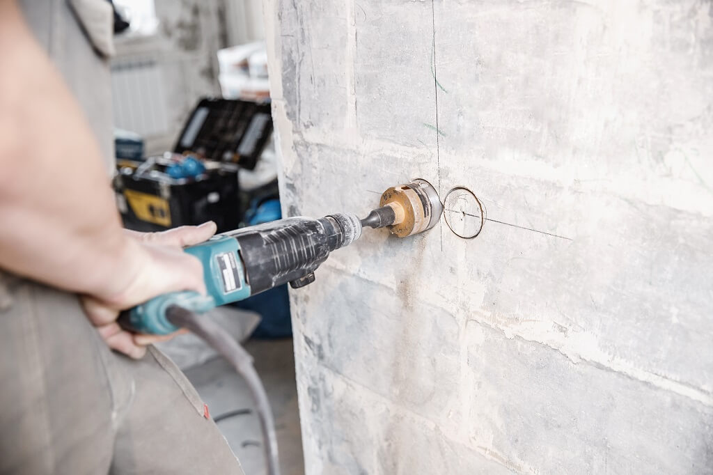 Precizno bušenje označenog mesta u betonu pomoću električne bušilice i krune