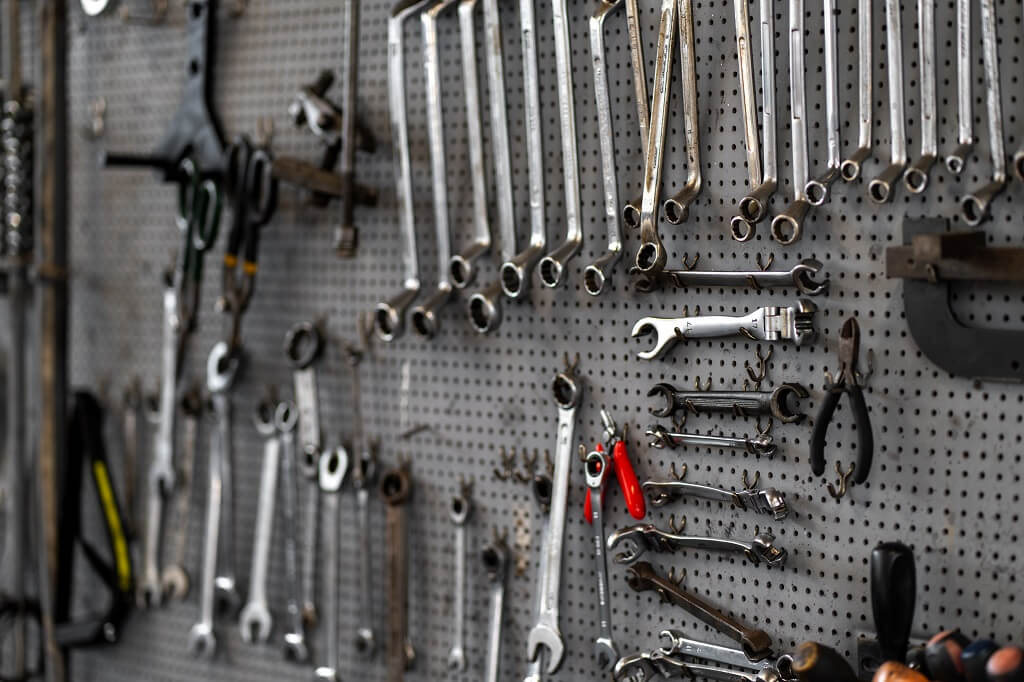 Zid sa uredno raspoređenim viljuškastim i okastim ključevima u radionici